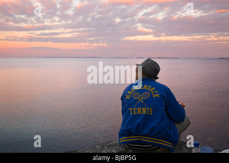 Junger Mann Essen auf einer Klippe direkt am Meer in den Schären von Stockholm. Stockfoto