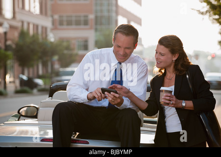 Kaukasische Geschäftsmann sitzt auf Auto-Text-messaging mit Mitarbeiter Stockfoto