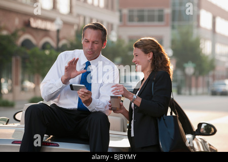 Kaukasische Geschäftsmann sitzt auf Auto-Text-messaging mit Mitarbeiter Stockfoto