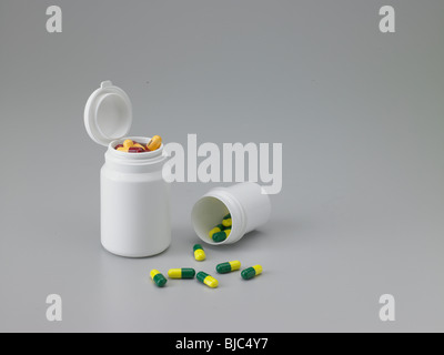 Tabletten aus einem medizinischen Behälter verschütten. Mittlere hohe Winkel. Stockfoto