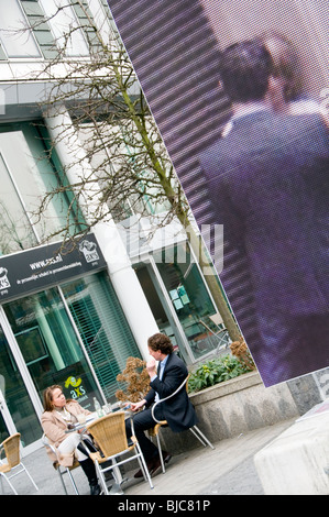 Zwei Menschen sitzen treffen vor einem Café in Amsterdam neben einem großen Outdoor-Kunstwerk Stockfoto
