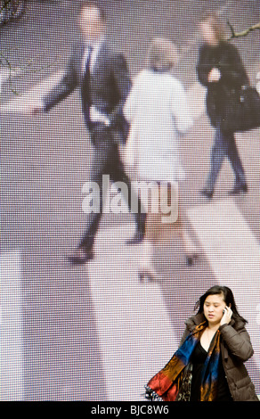 Eine Frau im Gespräch auf ein Mobiltelefon, vorbei an einem großen Outdoor-Kunstwerk in Amsterdam Stockfoto