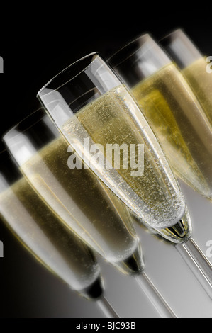 Studioaufnahme von Gläsern im Flötenstil, gefüllt mit Champagner auf dunklem, abgestuftem Hintergrund. Stockfoto