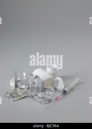 Abfälle Pharmaverpackungen und auch eine Spritze mit weißem Kunststoff Tablettenfläschchen in Hochformat und mittlere Ernte gedreht Stockfoto