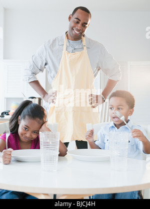 African American Vater Vorbereitung Abendessen für Kinder Stockfoto