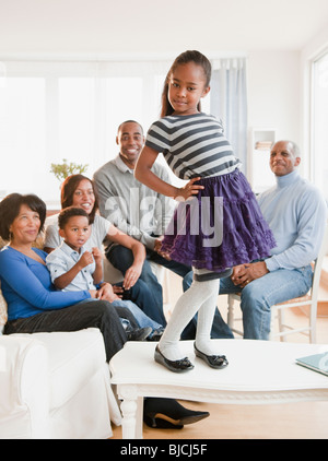 Afroamerikanische Familie beobachten Tochter auf Tisch stehend Stockfoto