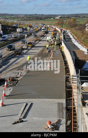 Bauarbeiter und Maschinen im Bauwesen arbeiten stark frequentierte M25-Autobahngebäude insgesamt vierspurige Straße Essex Landschaft England Großbritannien Stockfoto