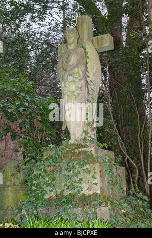 Highgate Cemetery in London, Grab mit Kreuz, Engel mit Kranz für Unsterblichkeit, eingestellt auf 3 Blöcke für glaube, Hoffnung & Nächstenliebe Stockfoto