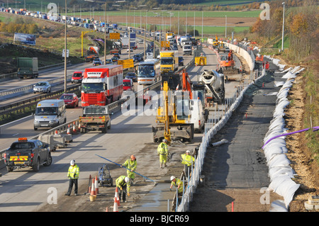 M25 Autobahnkontra Verkehrsstaus kommen unter Bauarbeitern zurück, die die Straße auf vier Fahrspuren in der Landschaft von Essex England Großbritannien verbreitern Stockfoto