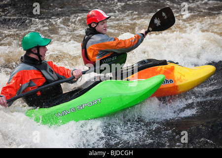 Zwei Kajakfahrer Kajak fahren im Wildwasser auf Tryweryn River. National Whitewater Center, Frongoch, Gwynedd, Wales, Großbritannien, Großbritannien. Stockfoto