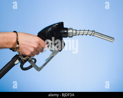 Hand mit Handschellen gefesselt an einer Zapfsäule. Stockfoto