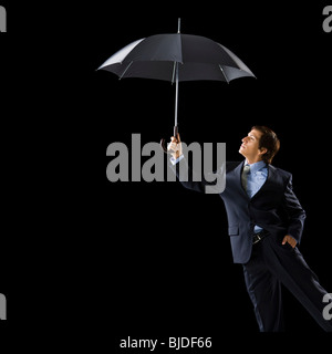 Junger Mann hält einen Regenschirm. Stockfoto