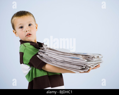 Kind hält einen Stapel Zeitungen Stockfoto