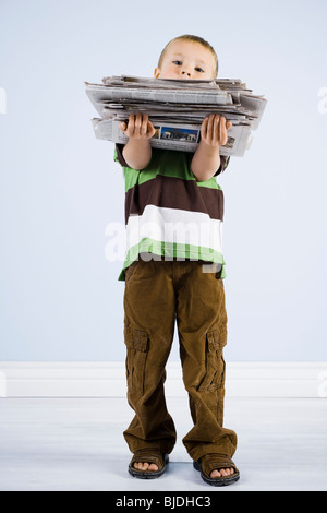 Kind hält einen Stapel Zeitungen Stockfoto