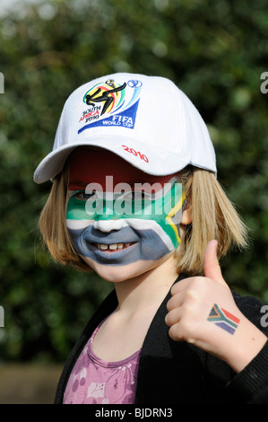 Porträt eines Mädchens mit Gesicht gemalt in den Farben der Nationalflagge der Republik Südafrika und trägt eine WM 2010 Mütze Stockfoto