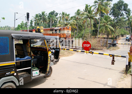 Auto-Rikschas warten im Bahnhof Kreuz für den Durchgang des elektrischen Train.Road Schienenoberkante cross Szene Indian Railways Stockfoto