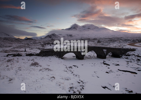 Eine Person, die zu Fuß über die Brücke Sligachan im Schnee, Isle Of Skye, Schottland Stockfoto