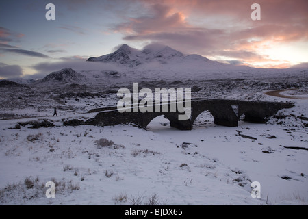 Eine Person, die zu Fuß über die Brücke Sligachan im Schnee, Isle Of Skye, Schottland Stockfoto