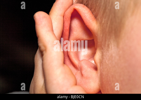 Foto eines Kindes mit der hohlen Hand hören Stockfoto