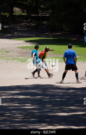 Drei Männer spielen mit Fußball im Stadtpark. Stockfoto