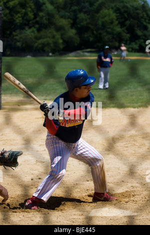 Baseball-Spieler bei Home-Plate, eine Fledermaus zu schwingen.  Schuss von hinten ein Maschendrahtzaun. Stockfoto