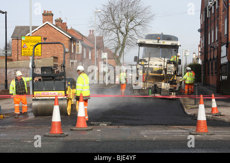 Arbeitnehmer, die Weiterleitung von Asphalt auf einer Straße in Großbritannien. Stockfoto