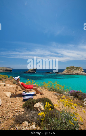 Frau sitzt in Sonnenliege, blaue Lagune, Comino, Malta Stockfoto