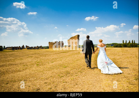 Braut und Bräutigam zu Fuß in Feld mit Ruinen, Rom, Italien Stockfoto