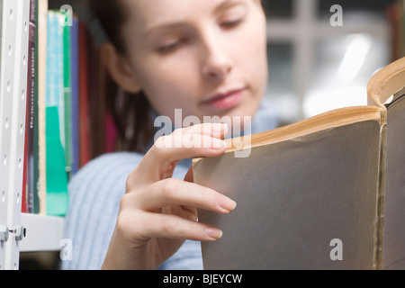 Junge Frau liest Buch in Bibliothek Stockfoto