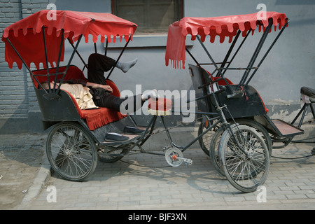 Fahrrad-Rikscha-Fahrer schlafen auf einer Seitenstraße in Peking, China. Stockfoto