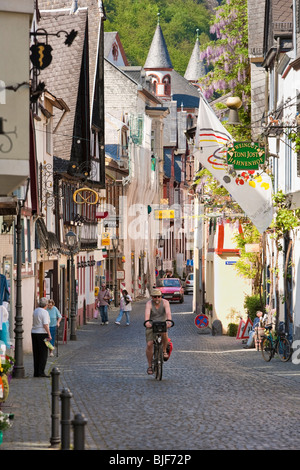 Mann, Radfahren und Menschen beim Einkaufen in Bacharach im Rheinland Deutschland - alte Straße mit Fachwerkhäusern Stockfoto