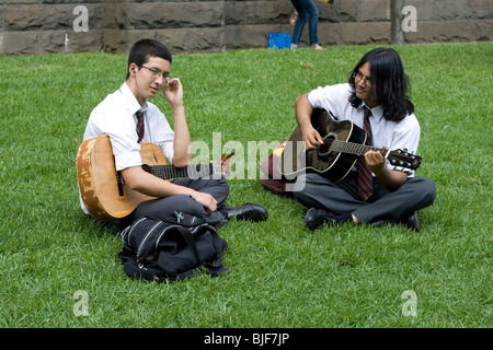 2 Schüler Gitarre spielen zusammen auf dem Rasen in Melbourne, Australien. Stockfoto