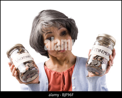 Frau mit zwei Gläsern von Münzen Stockfoto