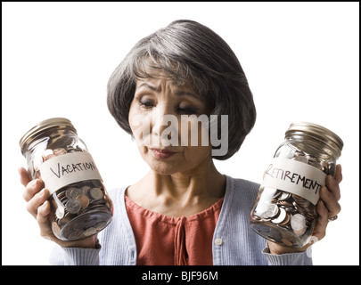 Frau mit zwei Gläsern von Münzen Stockfoto