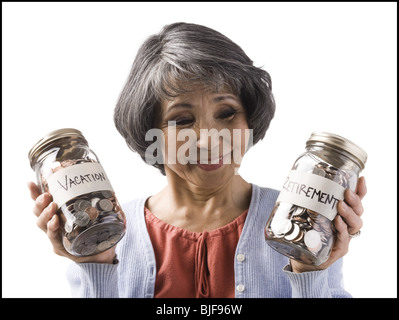 Frau mit zwei Gläsern von Münzen Stockfoto