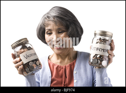 Frau mit zwei Gläsern von Münzen Stockfoto