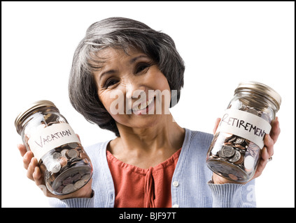 Frau mit zwei Gläsern von Münzen Stockfoto