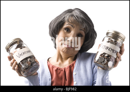 Frau mit zwei Gläsern von Münzen Stockfoto