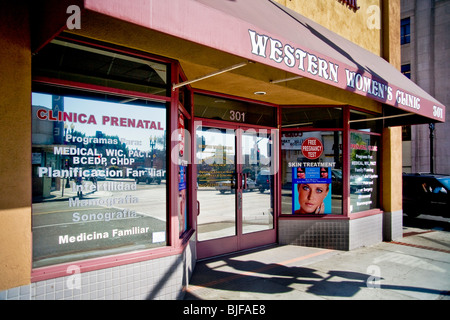 Ein Schaufenster Womens Klinik listet Dienste in Englisch und Spanisch oder "Spanglish" Fenster Zeichen in ein "Barrio" in Kalifornien Stockfoto