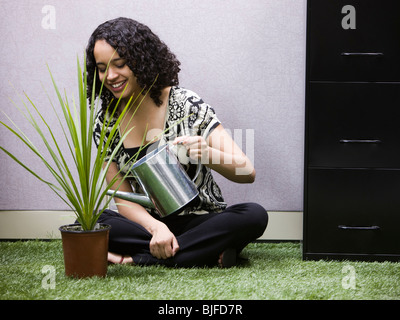 Frau, Bewässerung eine Pflanze in ihrem "grünen" Büro Stockfoto