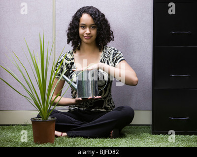 Frau, Bewässerung eine Pflanze in ihrem "grünen" Büro Stockfoto