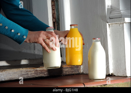 Flaschen Milch und Orangensaft vor einer Haustür geliefert von Milchmann UK Stockfoto