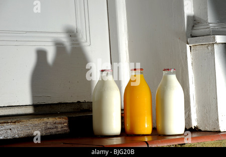 Flaschen Milch und Orangensaft vor einer Haustür geliefert von Milchmann UK Stockfoto