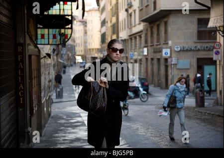 Florenz, Toskana, Italien. Attraktive schicke Frau geht über die Ponte Vecchio am Weg zur Arbeit in den Morgen. Stockfoto