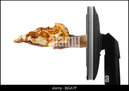 Hand, die aus einem Computer mit einem Stück pizza Stockfoto