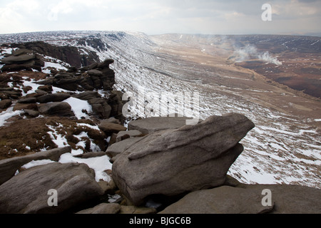 Winter am Nordrand der Kinder Scout in der Peak District National Park, Derbyshire, UK. Heather in der Ferne brennen Stockfoto