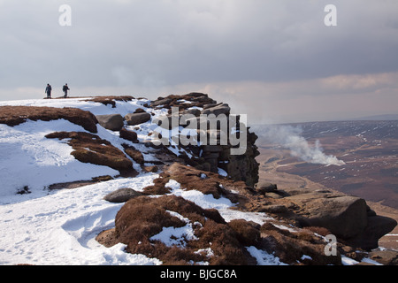 2 Wanderer im Winter am nördlichen Rand der Kinder Scout. Wildhüter sind brennende Heide im Hintergrund Stockfoto