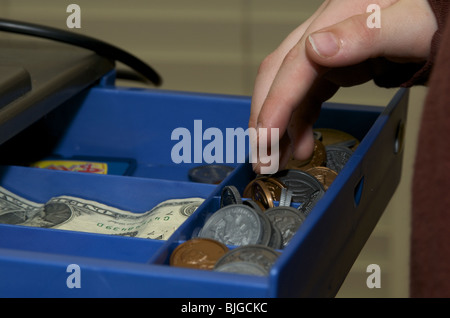 Kind greift nach Geld in eine Kasse Stockfoto