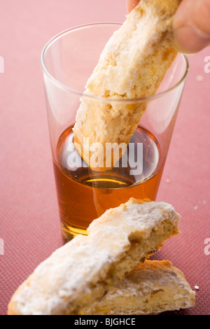 Hand eintauchen Cantucci (italienisches Mandel Keks) in Glas Vin Santo- Stockfoto