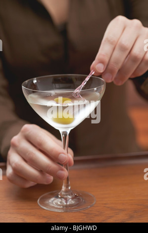 Frau aufspießen Olive im Martini-Glas- Stockfoto